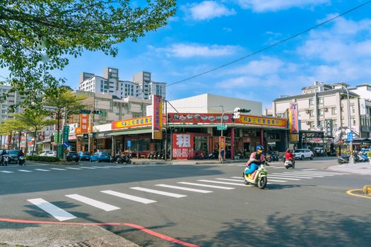 Vibrant city street scene in Kaohsiung City, Taiwan, featuring motor scooters and urban life.