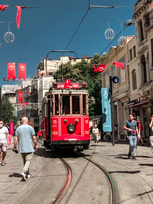 Free A classic red tram travels down a bustling street in Istanbul, lined with Turkish flags. Stock Photo