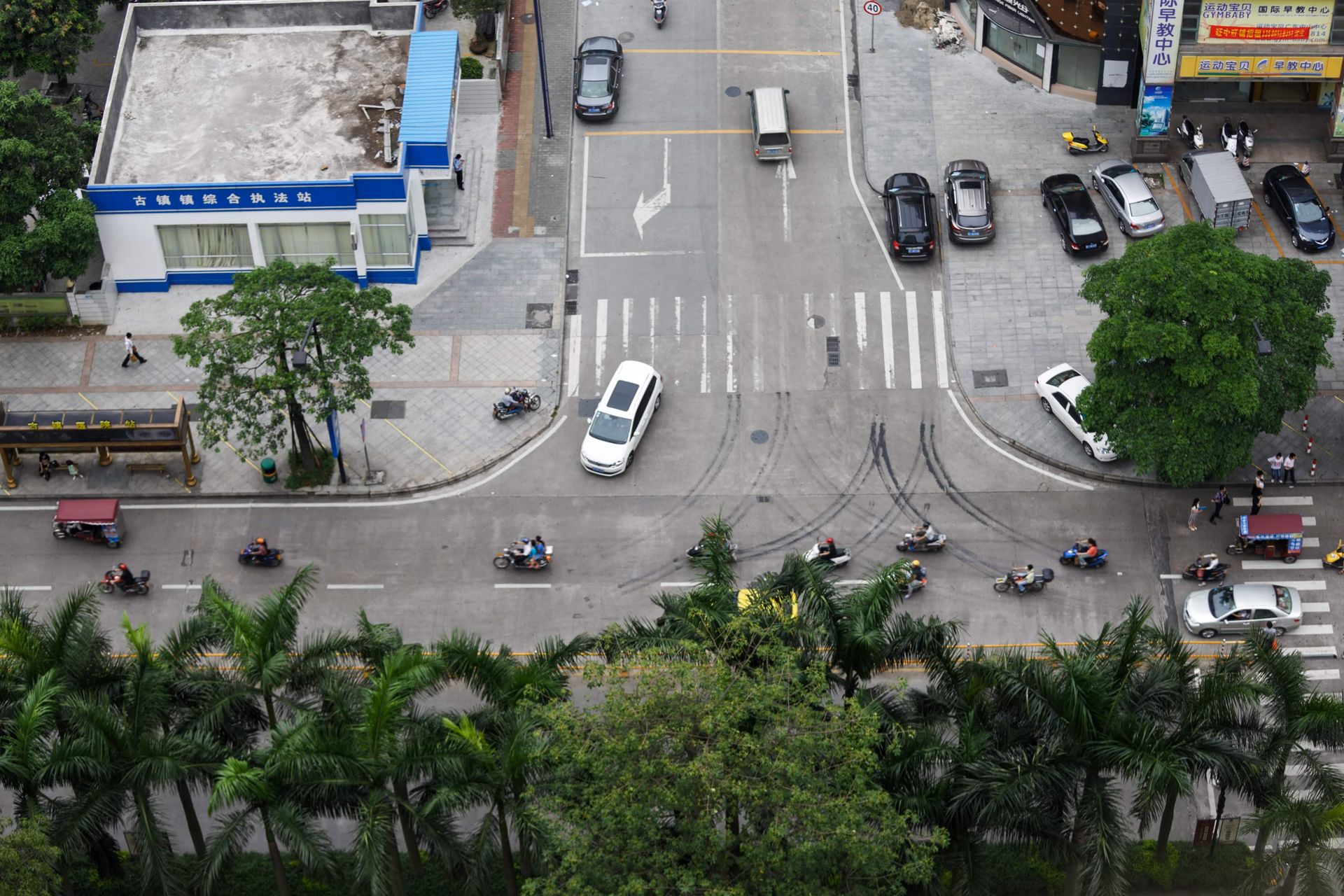 Overhead view of urban street intersection with cars and motorcycles, highlighting city life and transportation.