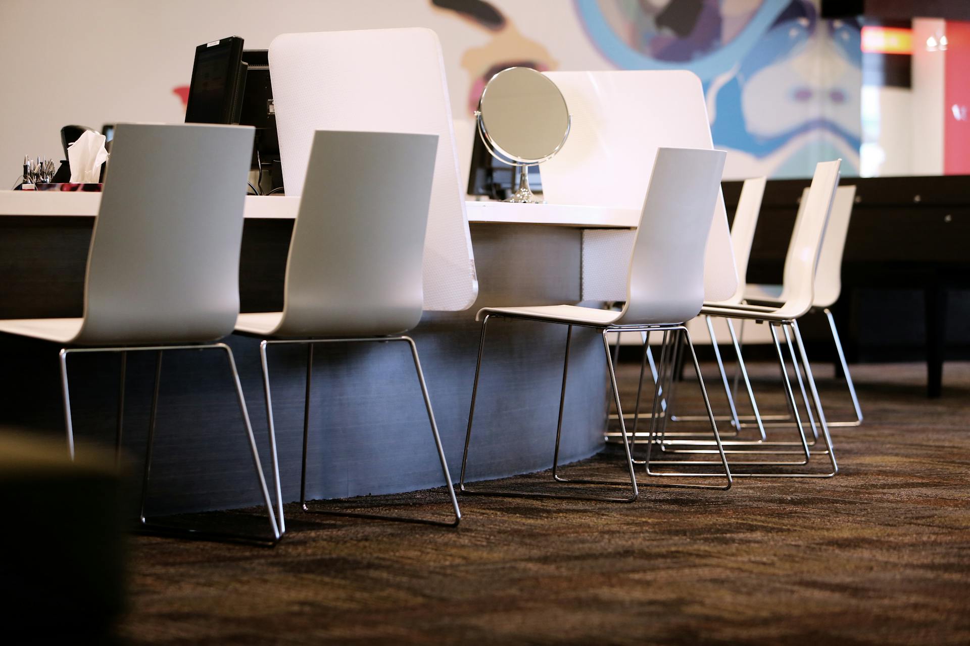 Contemporary office interior featuring white chairs and a vanity mirror on a table