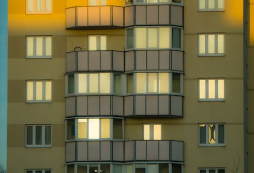 Free A modern apartment building with illuminated windows at sunset showcasing vibrant architectural details. Stock Photo