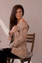 Attractive Young Woman in Trench Coat Sitting with Exposed Shoulder