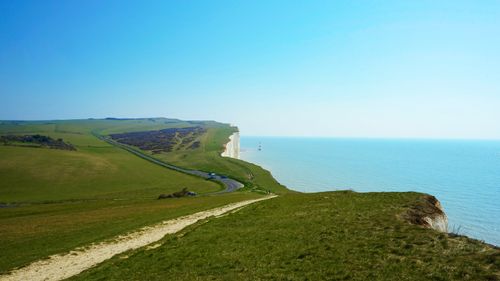 Free Sunny day at Beachy Head showcasing lush grass and clear blue sea. Stock Photo