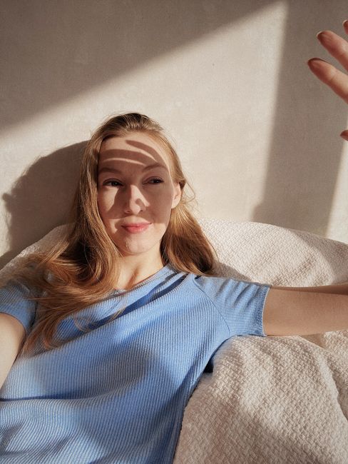A blonde woman enjoys gentle sunlight indoors, creating a serene morning vibe.