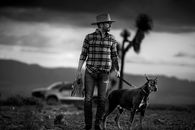Man in Fedora Hat Walking Doberman Dog with Six-Pack in Hand
