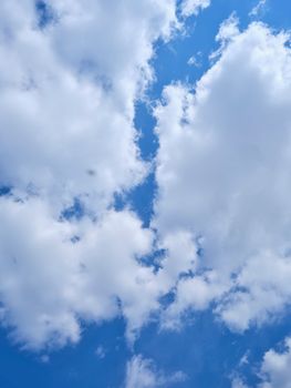 A beautiful view of fluffy white clouds drifting across a bright blue sky, evoking serenity.