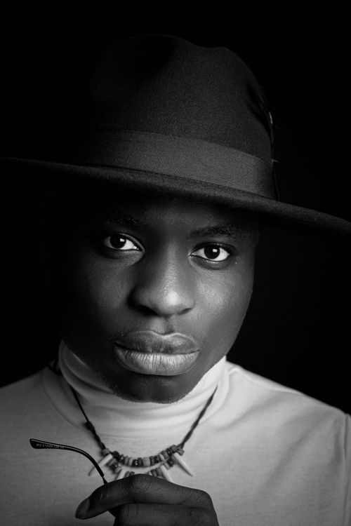 Free Black and white portrait of a man wearing a stylish hat and necklace, conveying elegance. Stock Photo