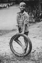 Kid Holding a Tire Standing on Dirt Ground