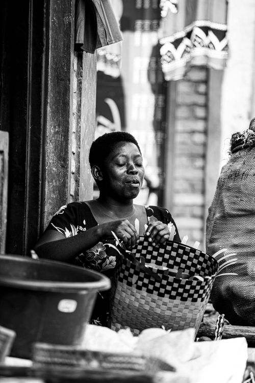 Free Monochrome portrait of a woman weaving a basket in an urban setting. Stock Photo
