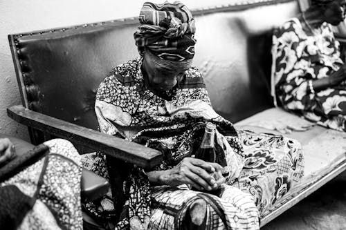 Elderly Woman Sitting on Leather Couch with Glass Bottle