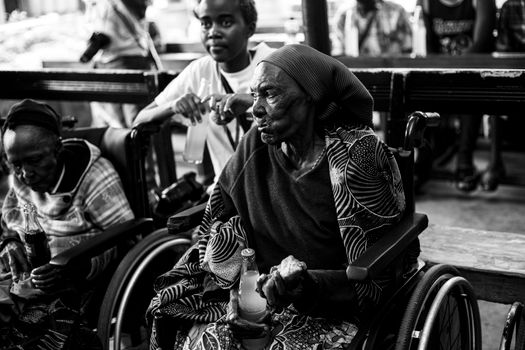 Black and white photo of elderly women in wheelchairs, socializing indoors.