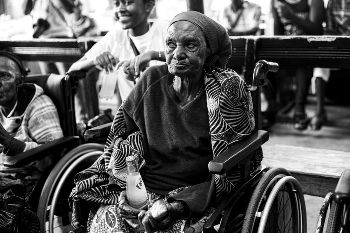 Elderly woman in a wheelchair in Uganda receiving support