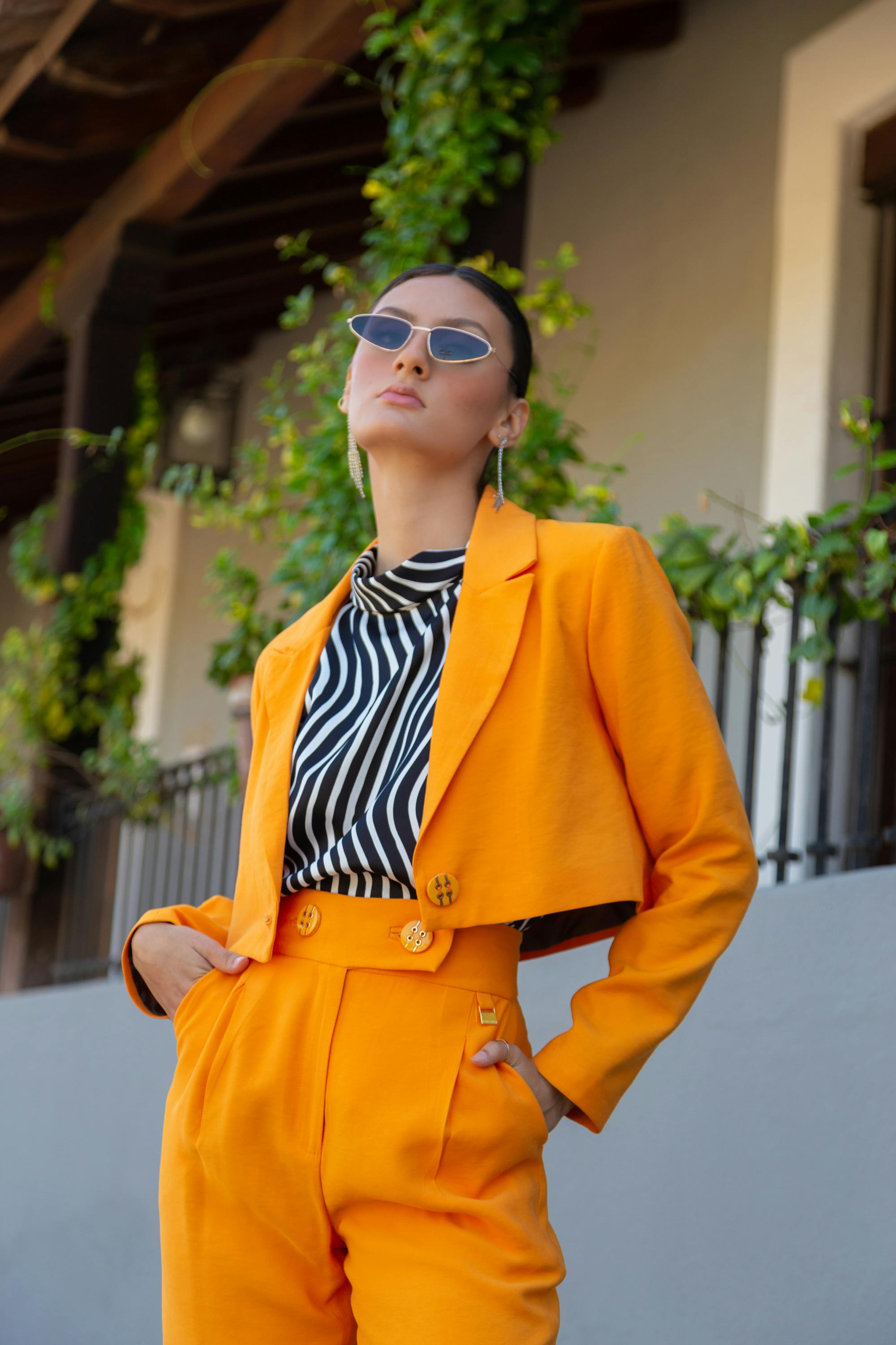 woman in sunglasses posing in orange suit