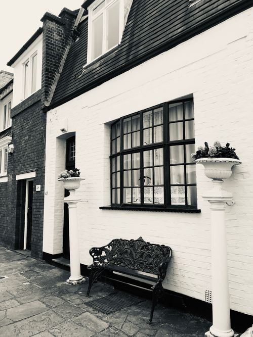 Free Stylish grayscale capture of a classic London townhouse featuring a vintage bench. Stock Photo