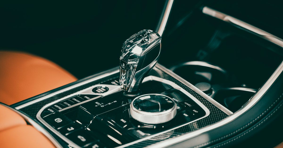 Close-up of a sleek gear lever in a luxury car interior featuring modern design elements.