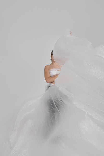 Artistic photograph of a woman obscured by flowing plastic, creating a surreal and abstract feel.