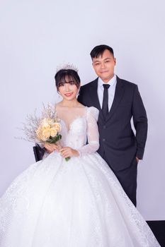 Charming Asian bride and groom smiling on their wedding day, elegantly posed with bouquet. - Fotografer Sidoarjo