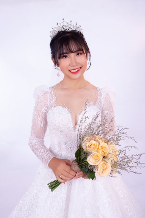 Free Beautiful bride in a lace wedding gown holding a bouquet of roses and smiling. Stock Photo