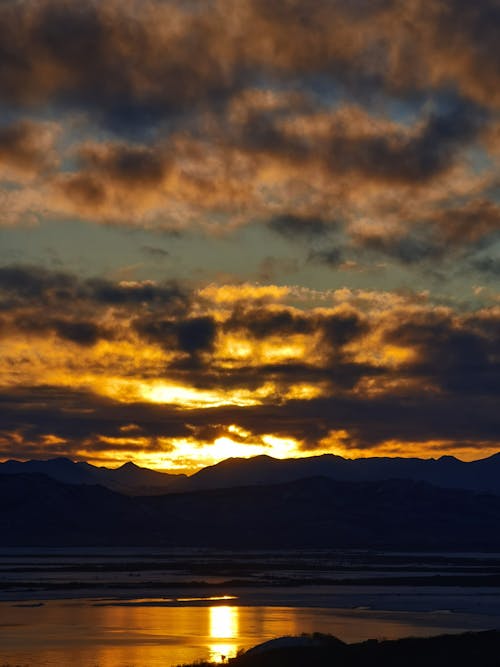 Silhouette of Mountains Under Cloudy Sky during Dusk 