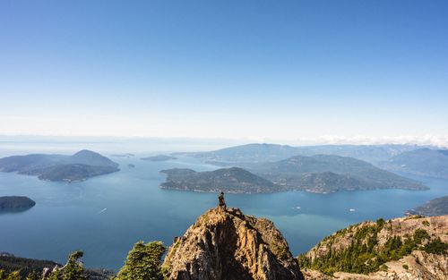 Free Hiker standing on mountain peak overlooking scenic lakes and islands in British Columbia, Canada. Stock Photo