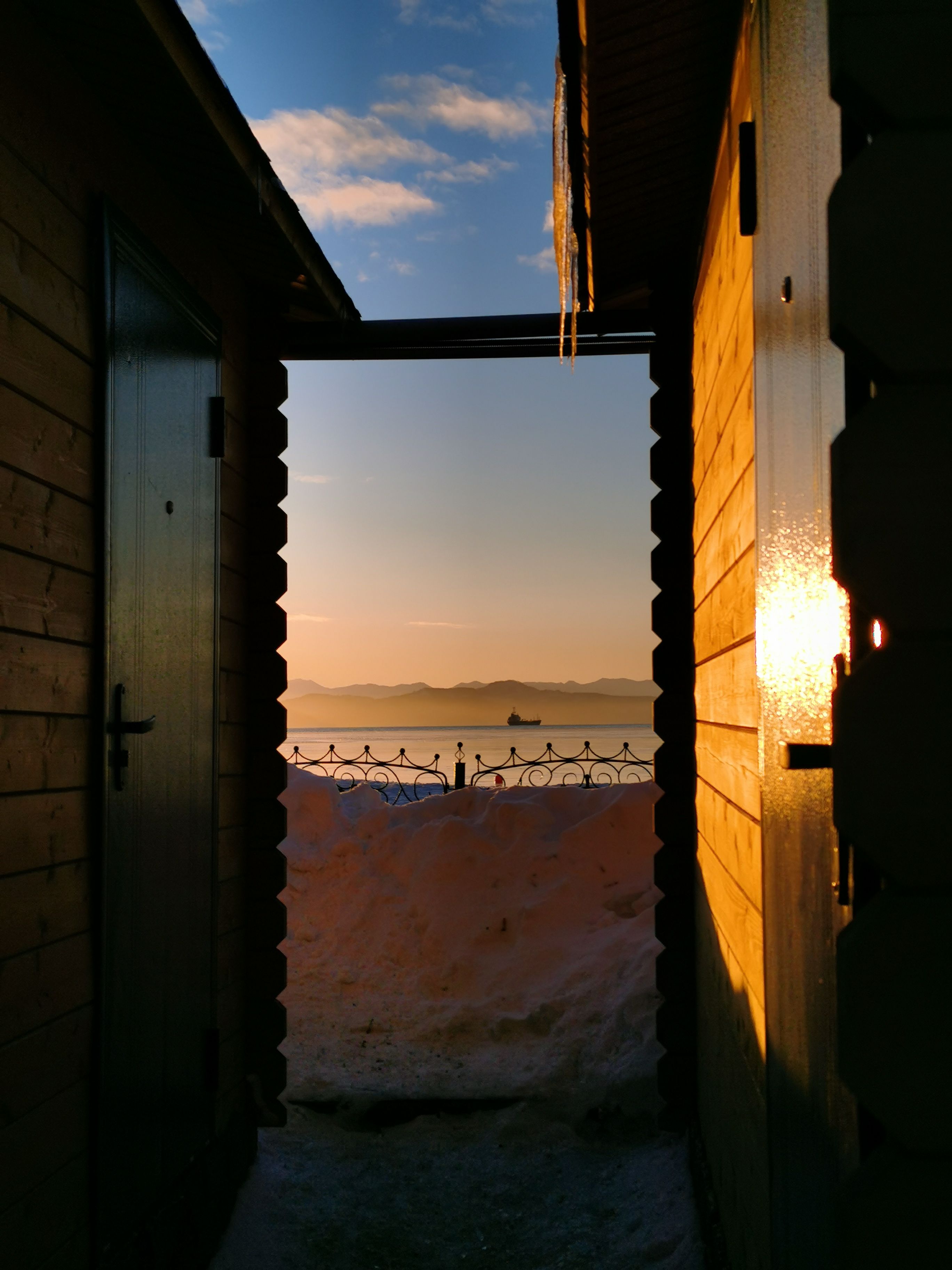 Captivating winter sunset through a doorway over snowy landscape.