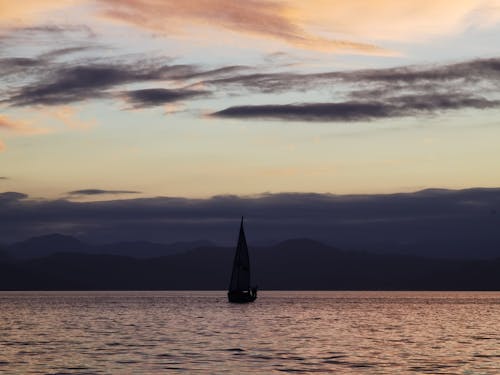 Free A Silhouette of a Sailboat at Sea Stock Photo