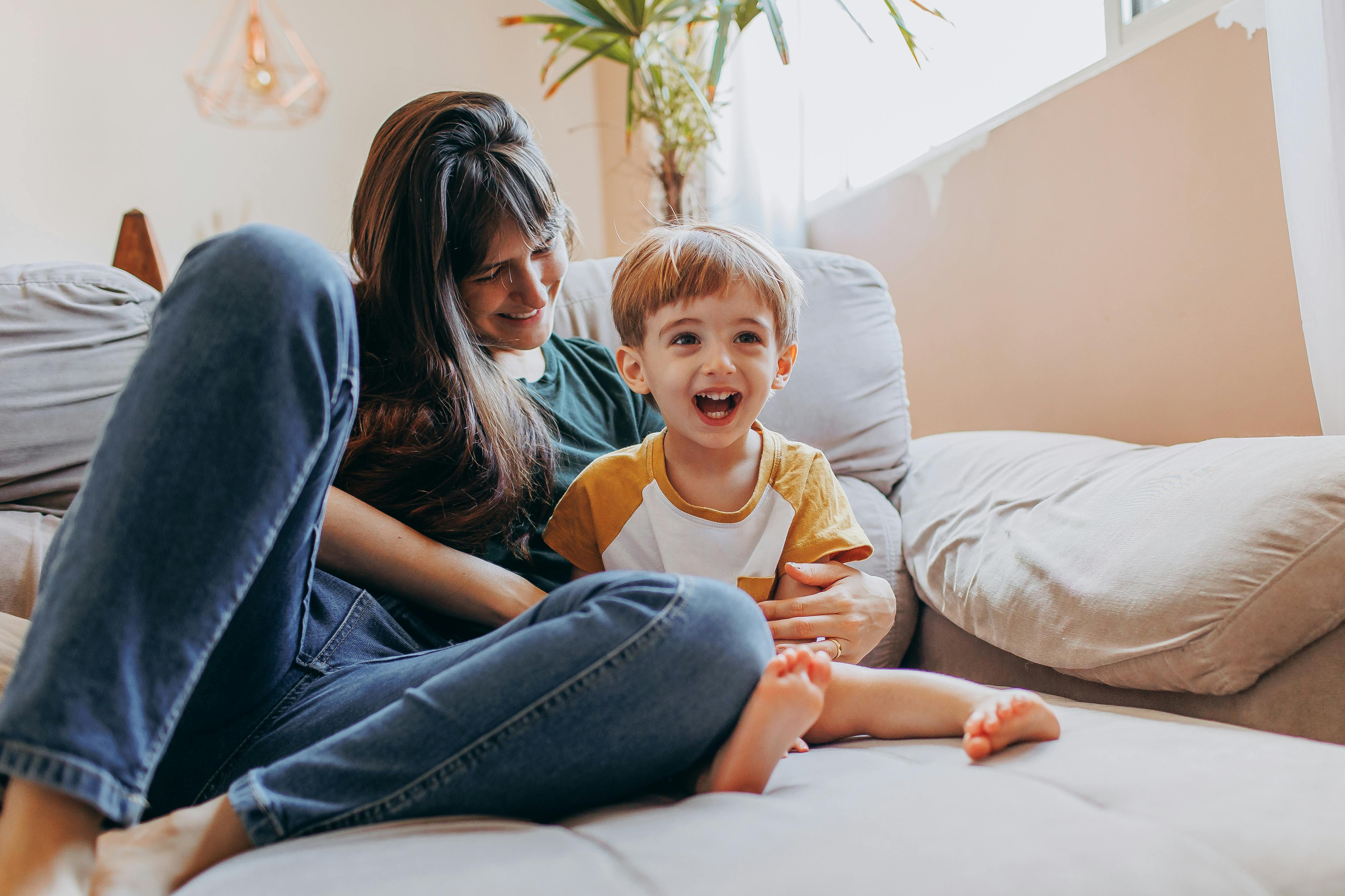 mother with son sitting on couch laughing