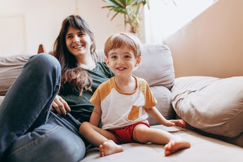 Mother and Son Smiling while Sitting on Living Room Couch