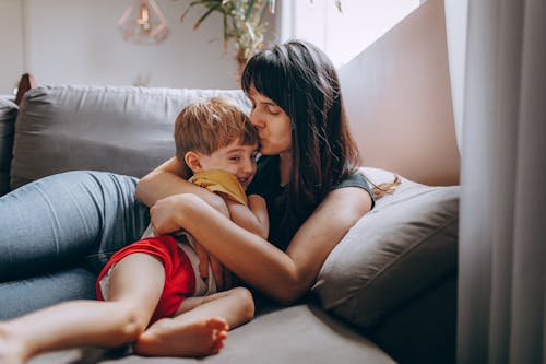 A Woman Kissing and Hugging her Son on a Couch