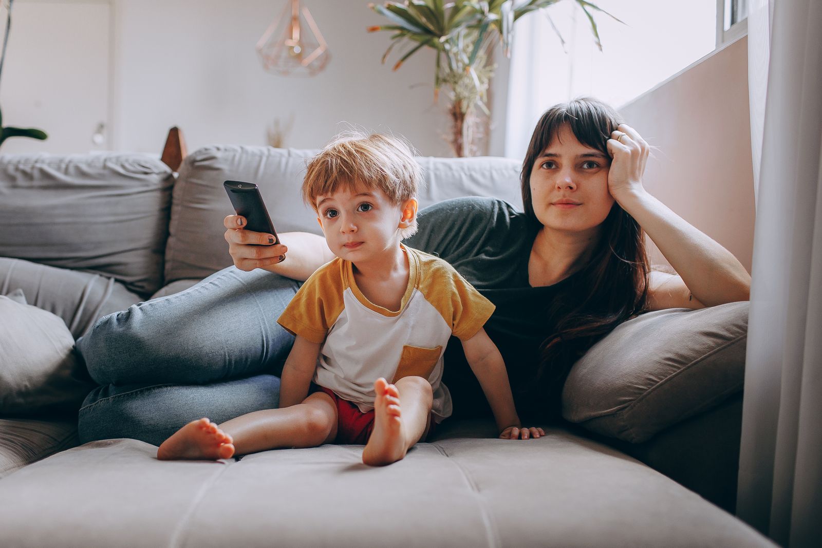 Overstimulated mom resting on a couch with her child during a loud and mentally full day at home