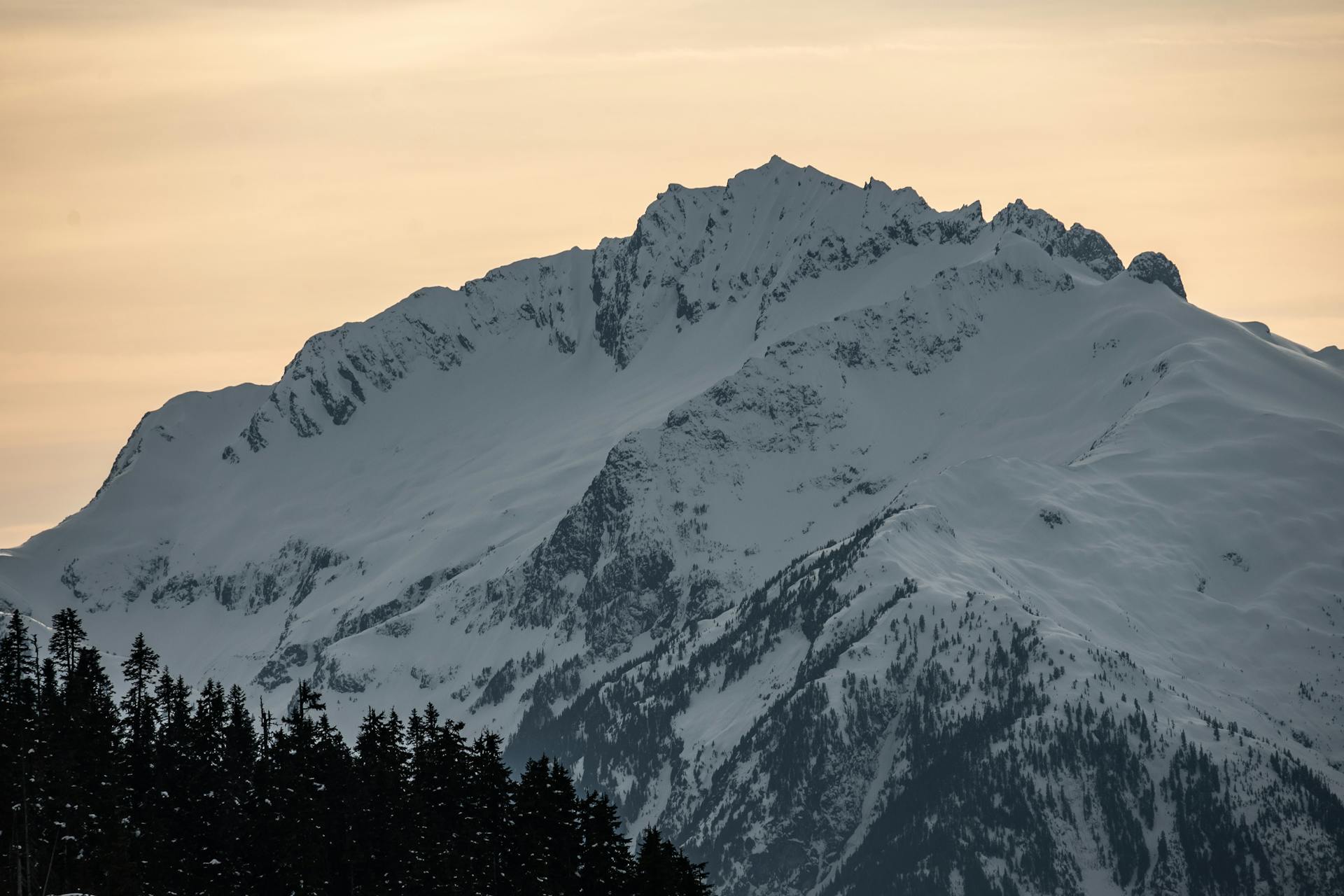 Serene view of snow-covered mountain peaks in British Columbia during winter sunset.