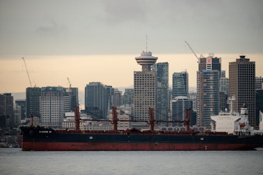 Cargo ship at Vancouver Harbor framed by city skyline. Urban and maritime elements.