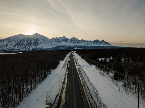 Drone Photography of a Country Road near Snow Capped Mountains 