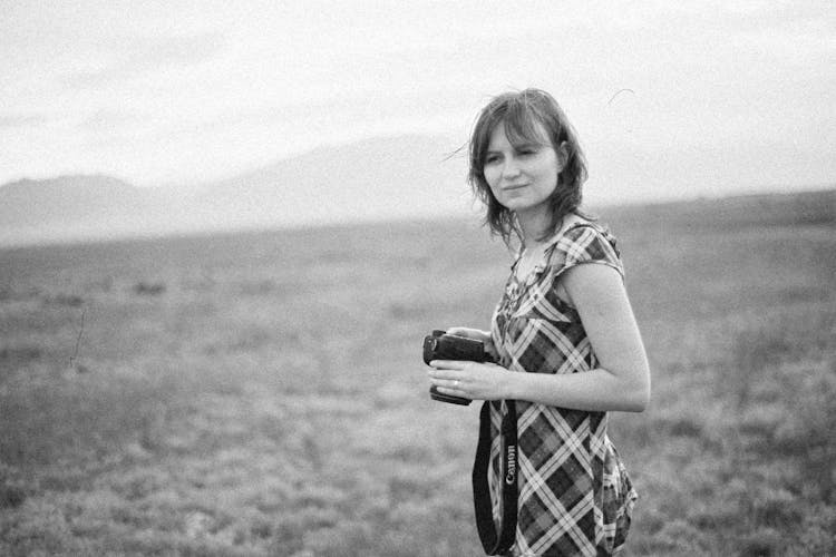 Young Woman Holding A Camera On A Field 