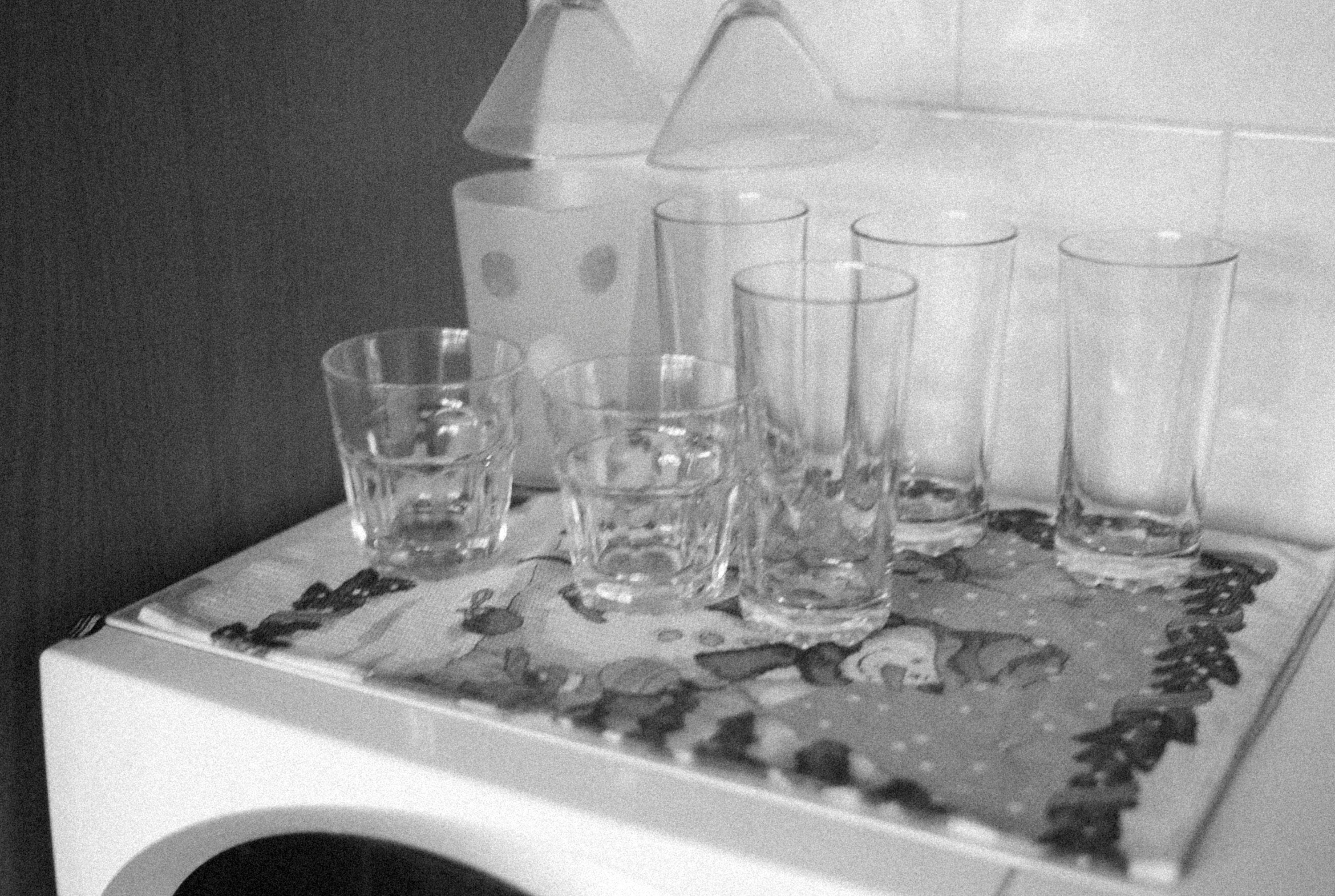 Black and white image of various glassware arranged on a festive mat in the kitchen.