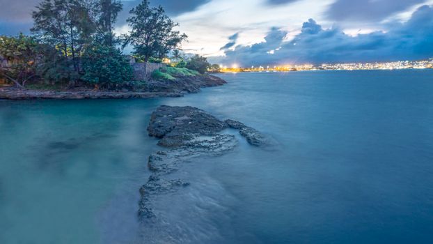 Scenic coastal view of Matanzas, Cuba during twilight, showcasing the tranquil ocean and distant city lights.