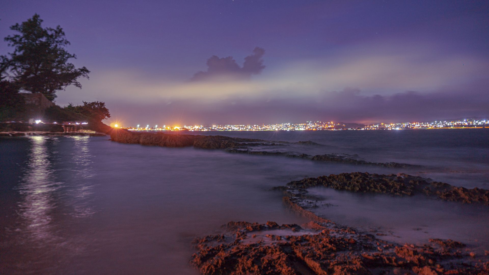 Stunning nighttime view of Matanzas, Cuba, with city lights reflecting on the calm sea.