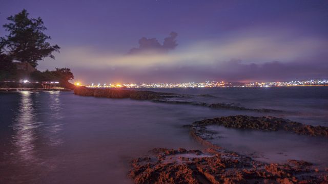 Stunning nighttime view of Matanzas, Cuba, with city lights reflecting on the calm sea.