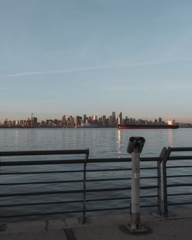 Gorgeous view of Vancouver's skyline with a calm river and ship during sunset.