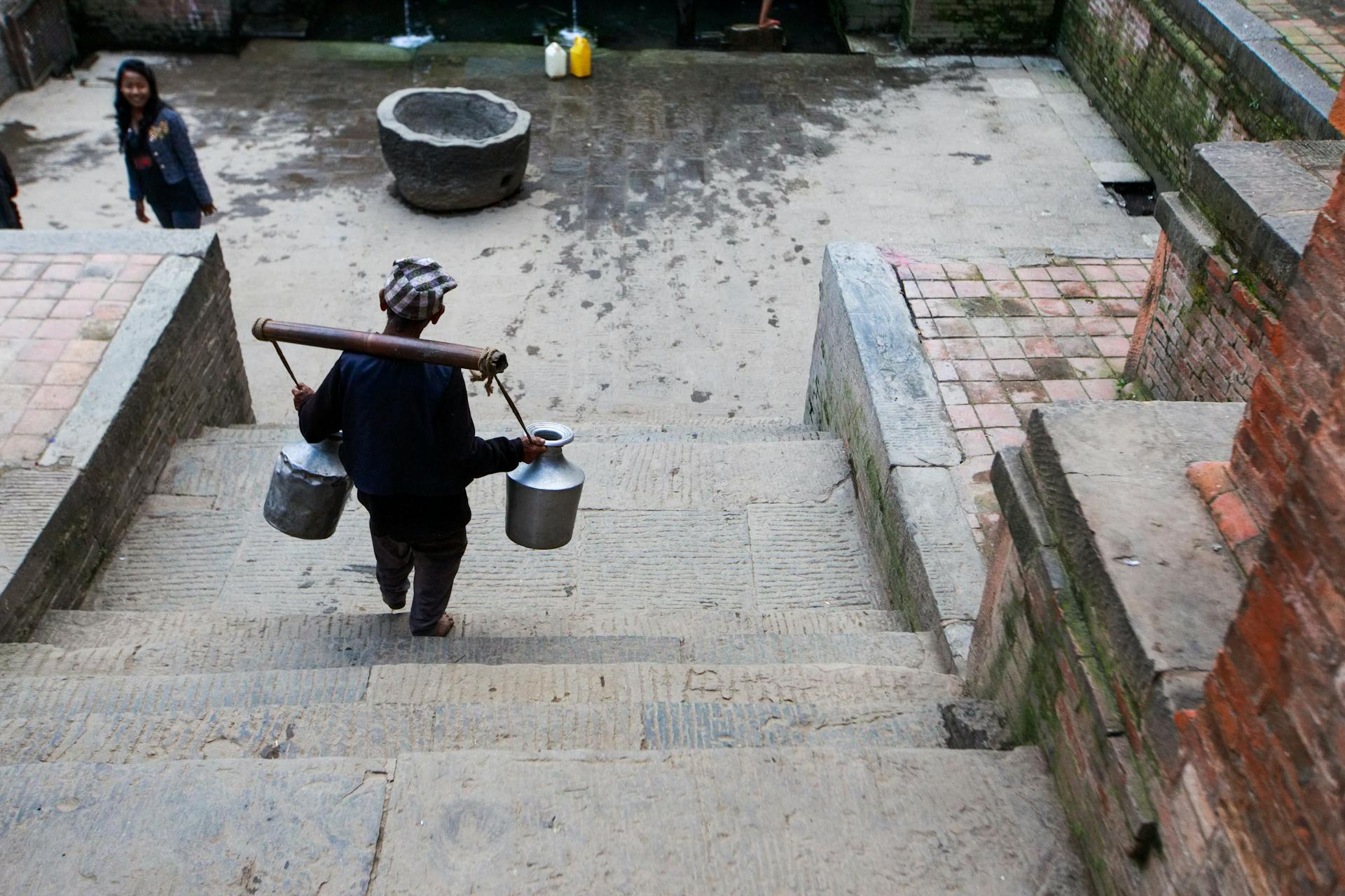 Back View of a Man Carrying a Two Jars while Walking