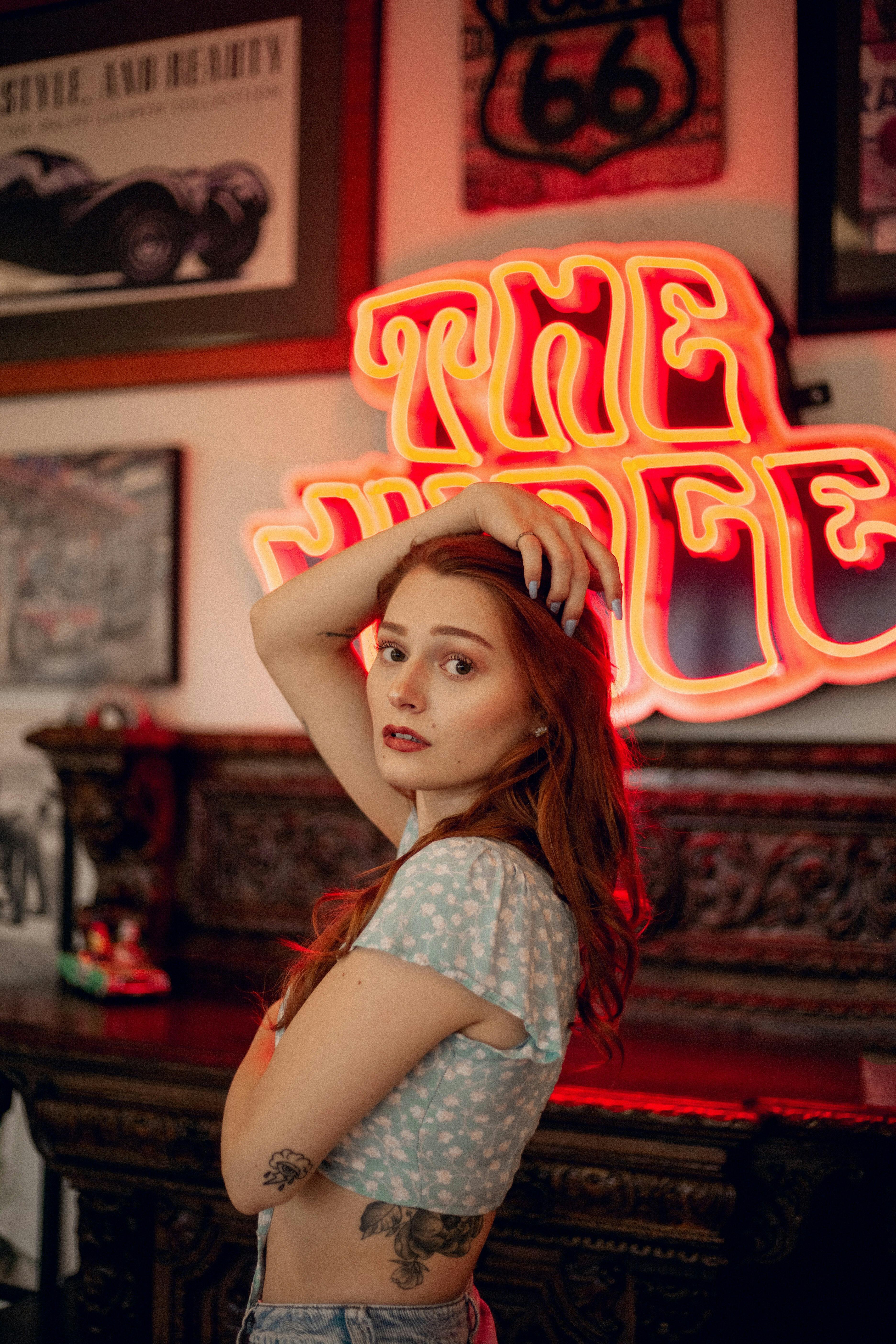 woman in vintage style clothes posing in front of neon sign