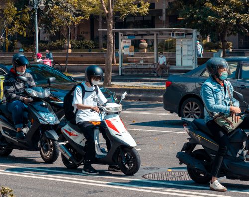 Free People riding scooters in a busy urban street with helmets and masks in Taipei. Stock Photo