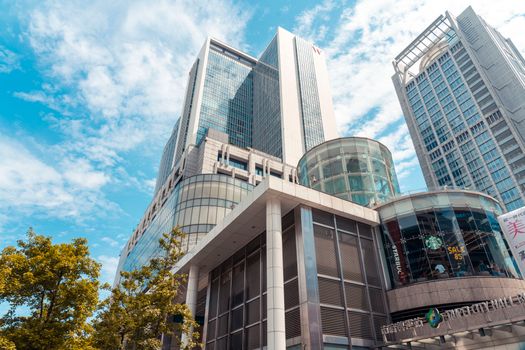 Low-angle view of modern skyscrapers with a blue sky in Taipei, capturing urban architecture.