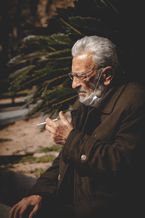 Elderly Man in Brown Coat Smoking Cigarette
