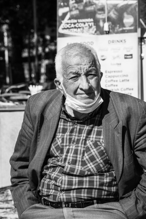 Free Elderly man wearing a face mask in a grayscale outdoor setting. Stock Photo