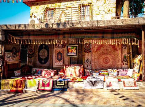 A vibrant display of traditional carpets and textiles outside a rustic store.