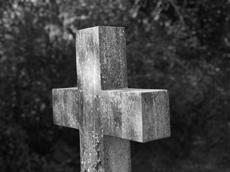 A detailed monochrome image of a weathered concrete cross in a London cemetery, conveying serenity.