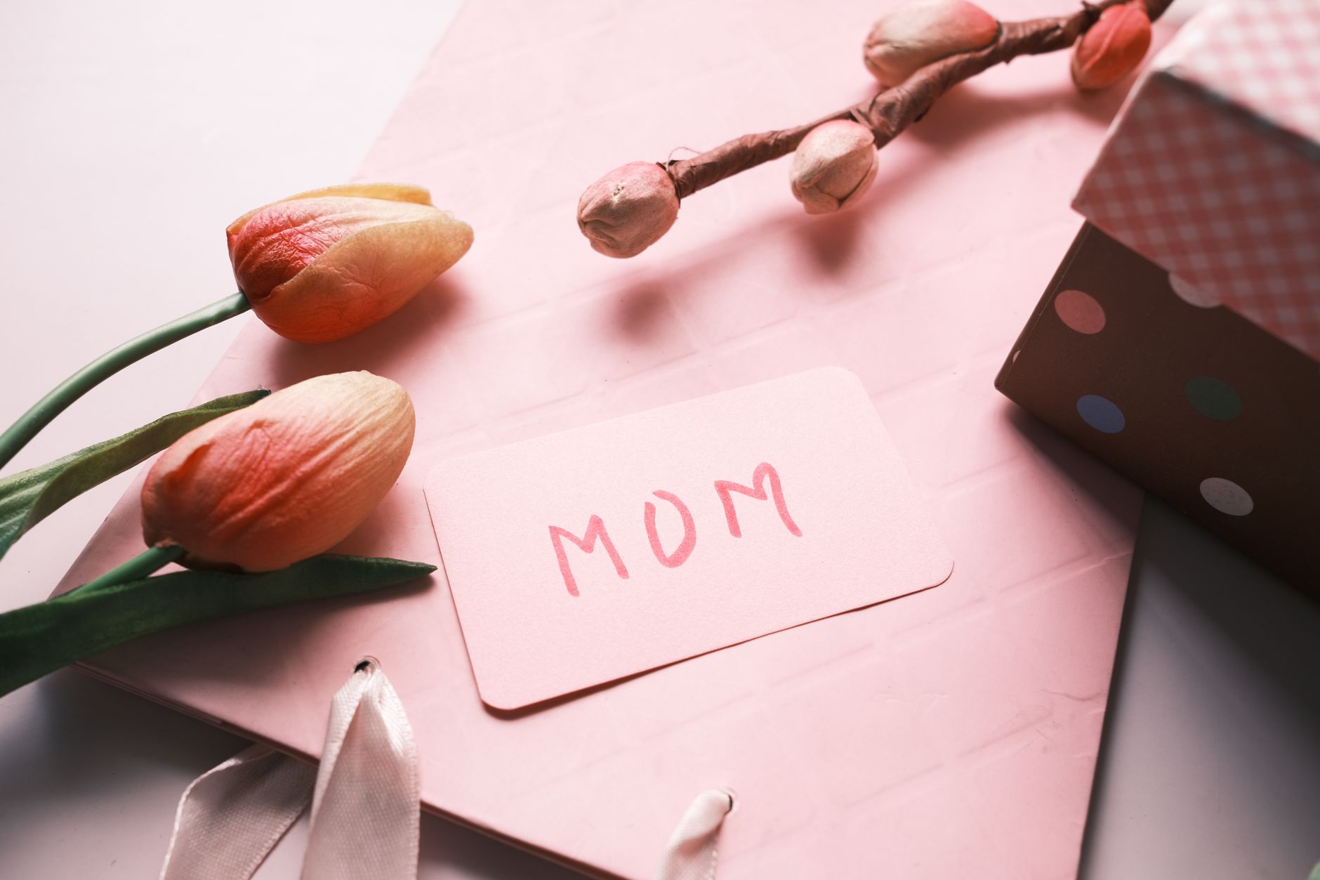 mothers day event planner egypt — Close-up of a Mother's Day card and tulips on a pink background, evoking warmth and appreci
