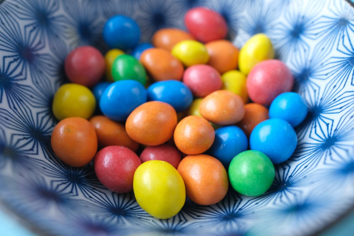 Vibrant candy shells in a blue patterned bowl, showcasing an array of colors.