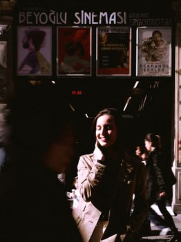 A woman smiles in the sunlight outside Beyoğlu Sinemasi, an urban cinema. - Fotografer Sidoarjo